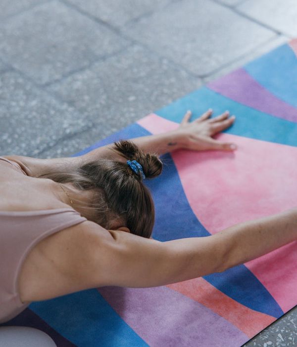 Person stretching on a yoga mat with magenta color accents.